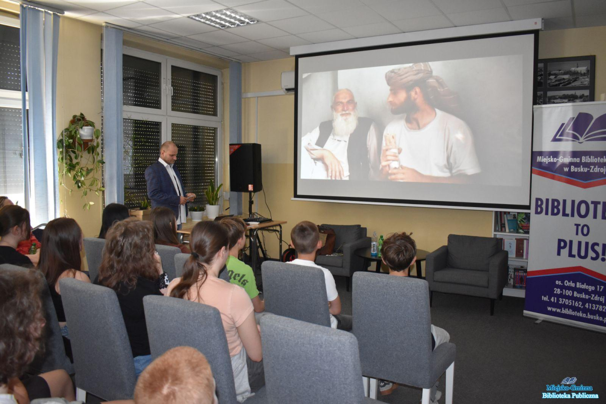 Dzieci siedzą i oglądają prezentację a Pan stoi obok