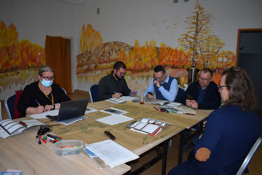 Kilka osób przy stole pracuje nad kartą pracy