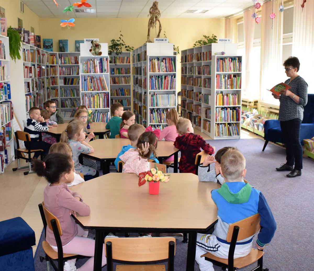 Pani czyta dzieciom, które siedzą przy stolikach