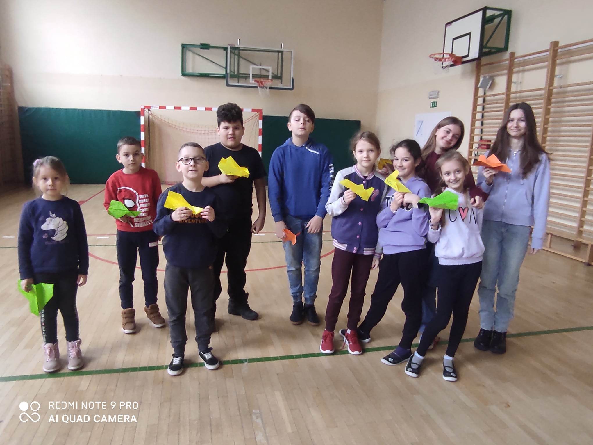 Grupa dzieci na hali sportowej pozuje do zdjęcia
