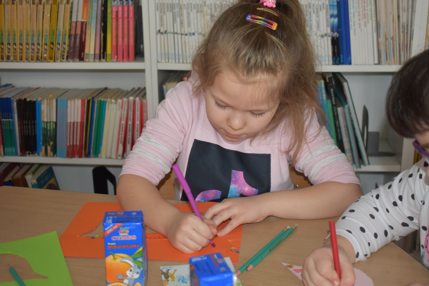 Dziewczynka koloruje prace plastyczną