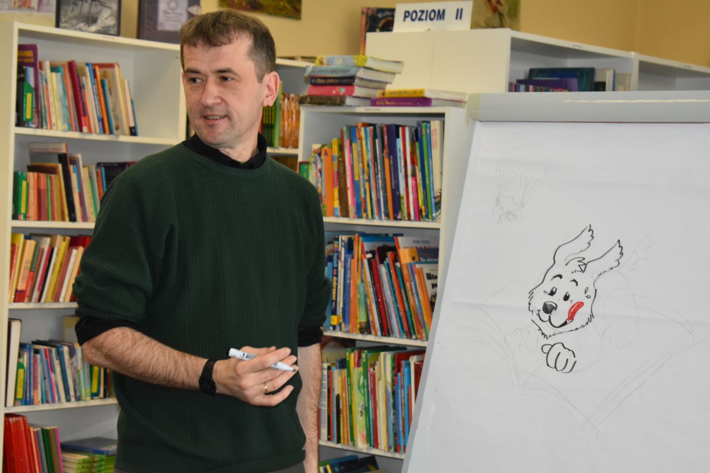 Pan zwraca się do dzieci podczas rysowania psa