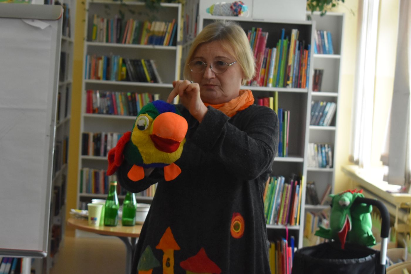 Pani trzyma w ręce maskotkę papugi