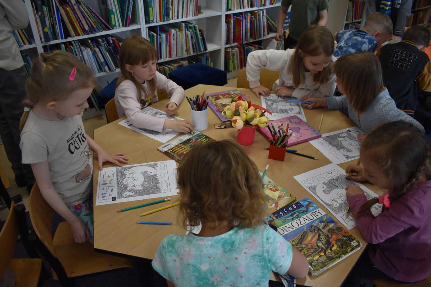 Dziewczynki siedzą przy stoliku i rozwiązują zagadki 