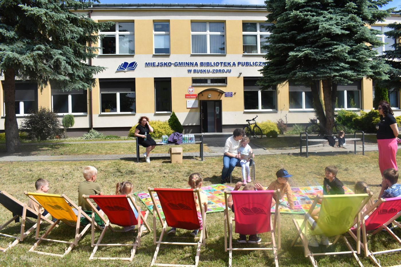 Pani z dziewczynką siedzi na krześle i czyta książkę
