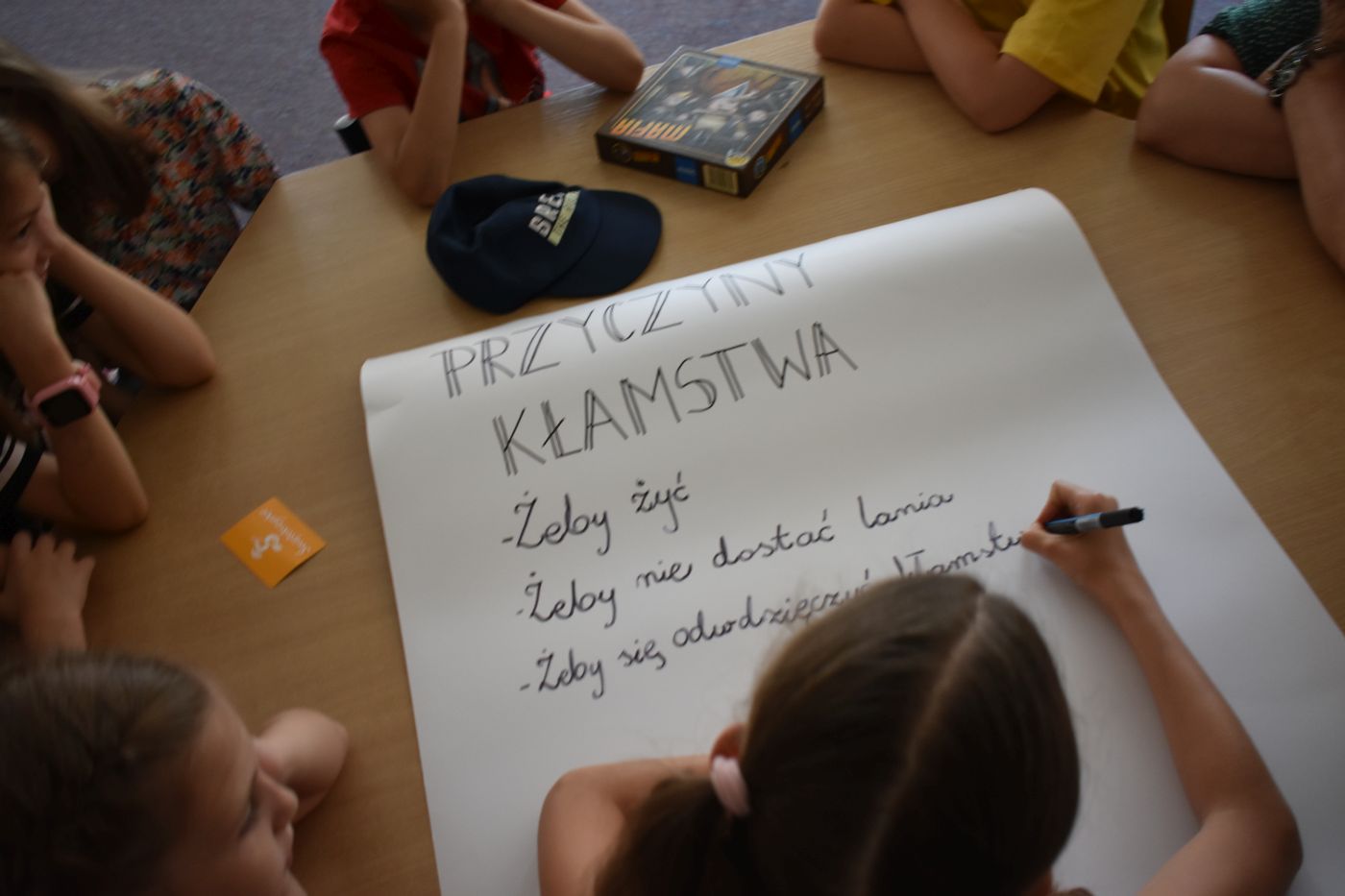 dziewczynka pisze na dużej białej kartce