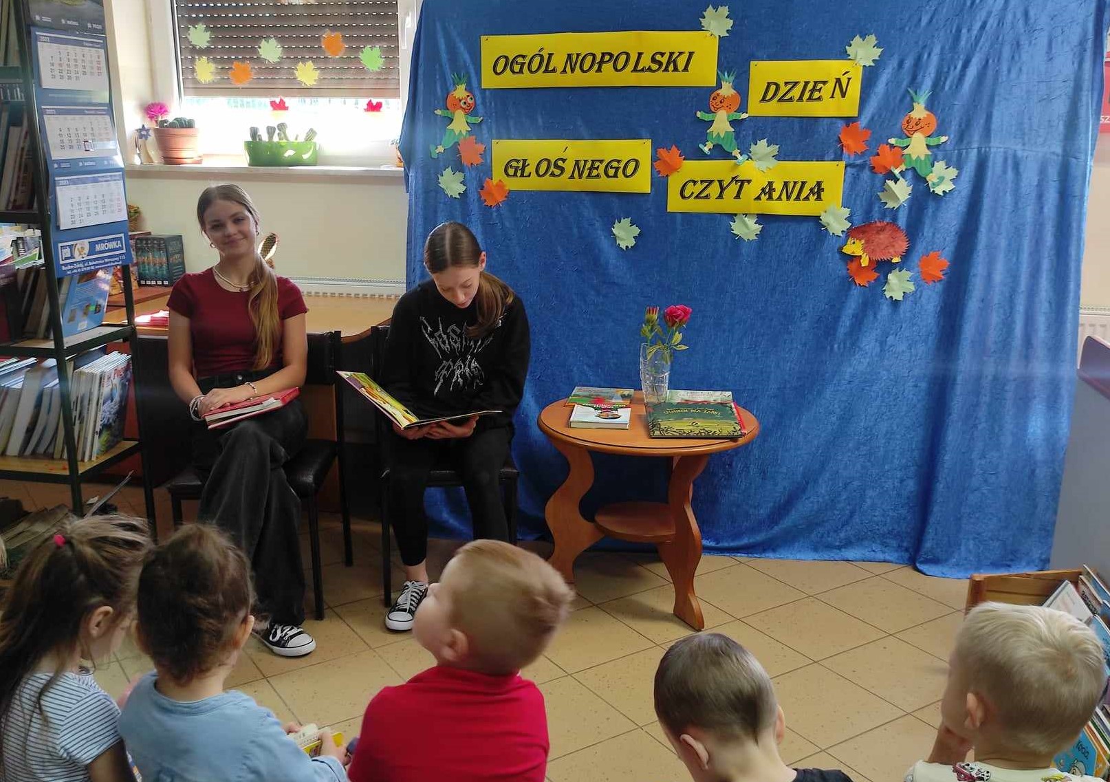 Dwie dziewczyny czytają książki dla zebranych dzieci