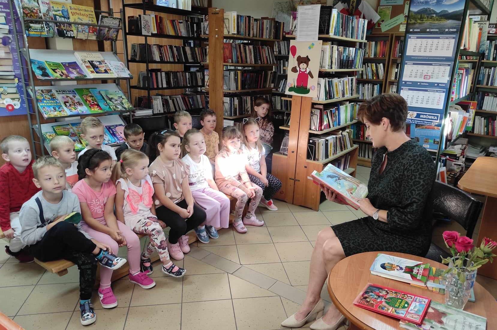 Pani czyta książkę zebranym dzieciom