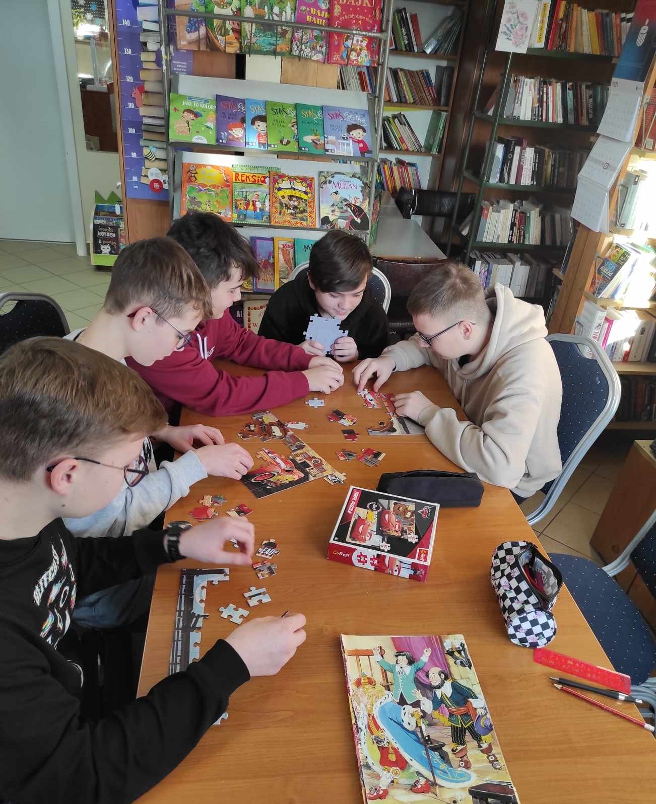 Pięciu chłopców układa puzzle przy stoliku