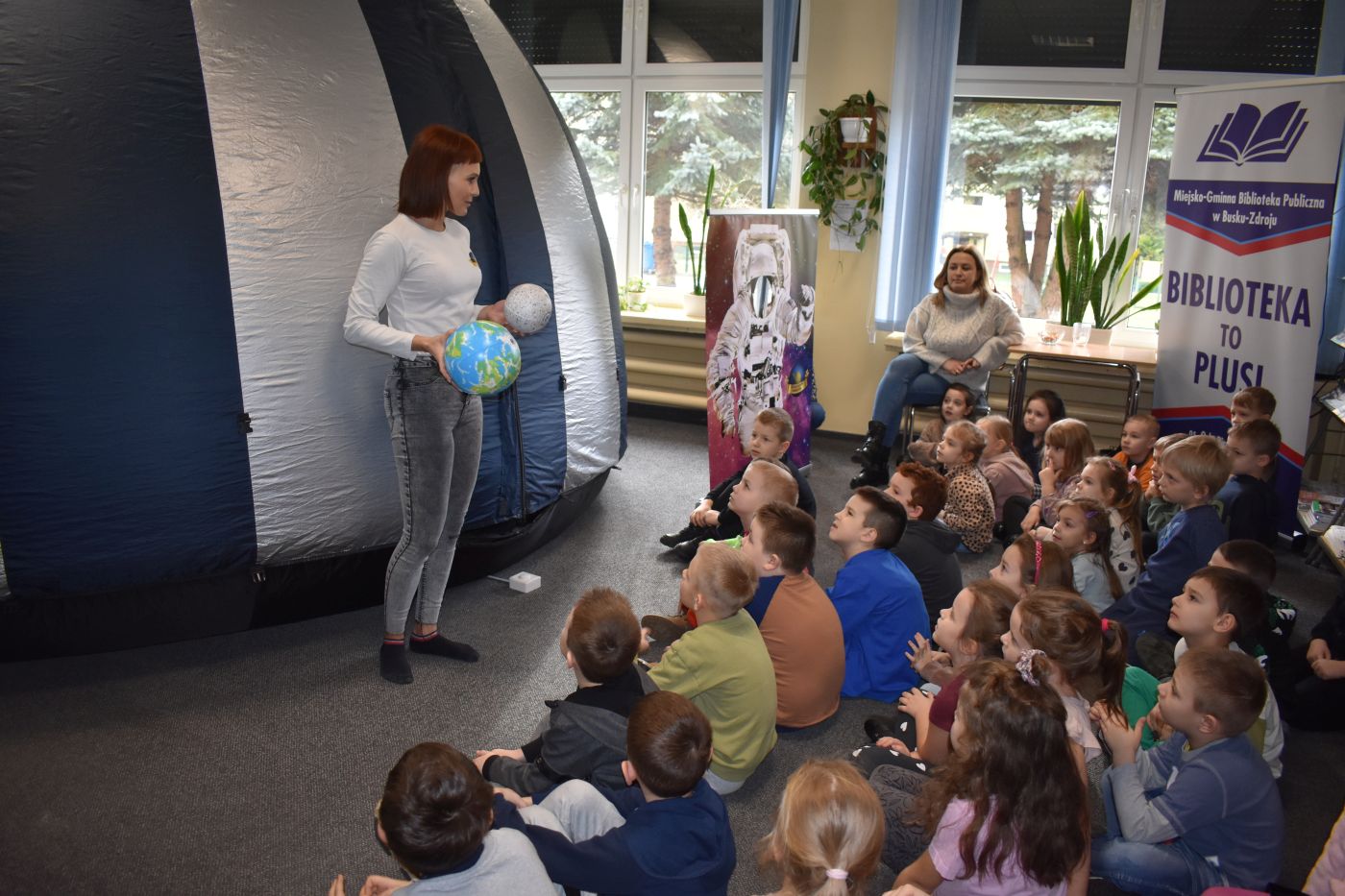 pani trzyma w dłoniach dwa modele planet
