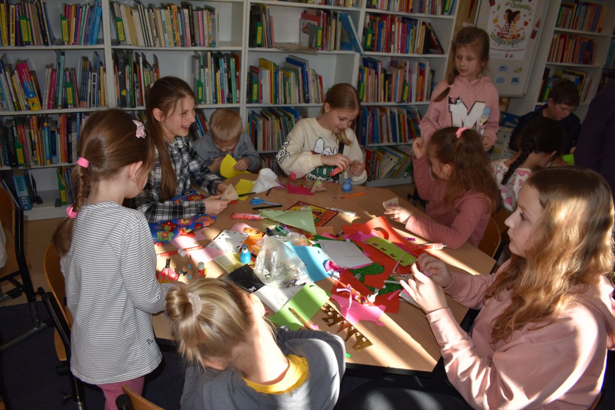 dzieci siedzą przy stoliku i wykonują prace plastyczne
