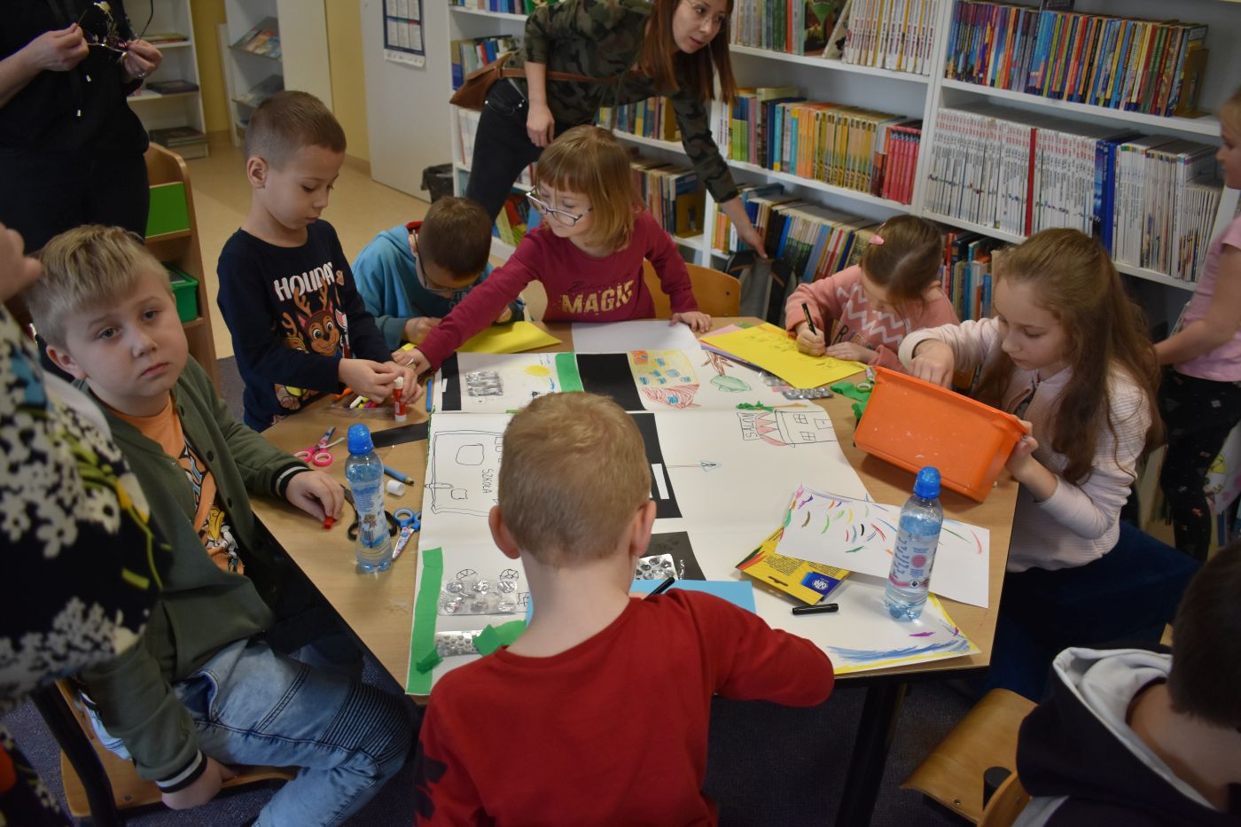 grupa dzieci wykonuje wspólny plakat