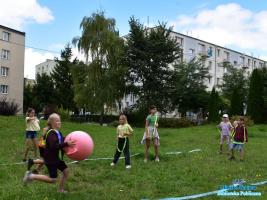 Dziewczynka biegnie trzymając w ręgu dużą piłkę
