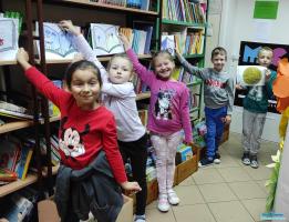 Dzieci pozują do zdjęcia przy półkach z książkami