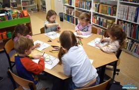 dzieci siedzą przy stoliku i kolorują