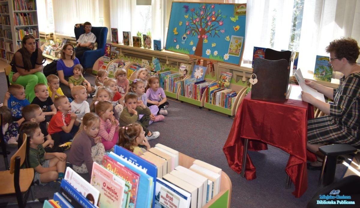 Pani czyta a dzieci siedzą na dywanie i słuchają