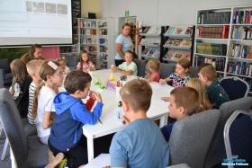Grupa dzieci siedzi przy stolikach