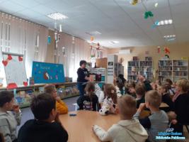 Pani wita dzieci, które siedzą przy stolikach