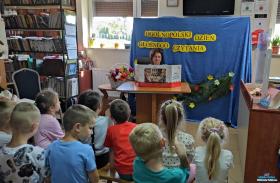 Pani bibliotekarz czyta dzieciom bajkę z teatrzyku kamishibai