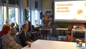 Pani stoi przy stoliku a goście siedzą