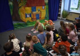 Aktorka leży na dywanie a obok siedzą dzieci