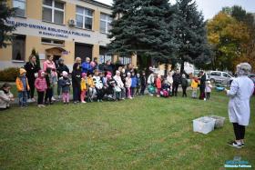 Grupa dzieci stoi na placu przed biblioteką
