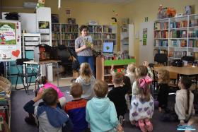 Pani pokazuje dzieciom, które siedzą na podłodze książkę