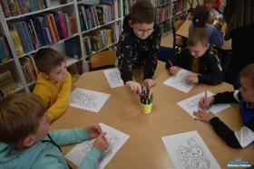 Pięciu chłopców siedzi przy stoliku i kolorują obrazki