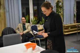 Kobieta trzyma sztućce i stoi obok stołu na którym stoją miski z jedzeniem