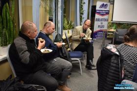 Mężczyźni spożywają posiłek siedząc i dyskutując