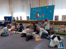 Dziesięcioro dzieci siedzi na podłodze i ogląda książki