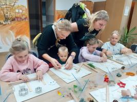 Czworo dzieci i dwie mamy wykonują prace plastyczne