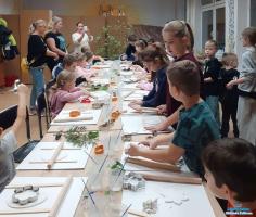 dzieci stoją przy stole i robią prace plastyczne