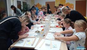 dzieci z rodzicami wykonują prace z gliny przy stoliku