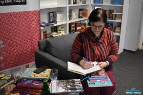 Pani podpisuje książkę dla biblioteki