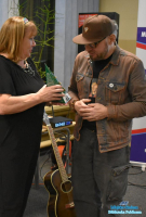 Kobieta przekazuje prezent w postaci małej choinki mężczyźnie w czapce