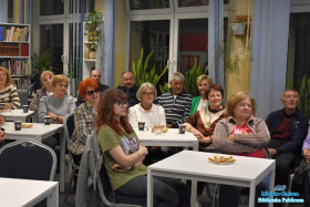 Ludzie siedzą przy stolikach i się uśmiechają