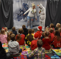 Pani w czapce na głowie oraz pan w przebraniu bałwana stoją przed dziećmi