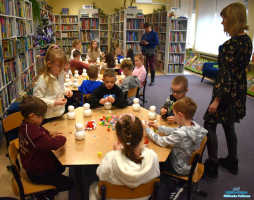 Dwie Panie stoją przy stolikach a dzieci siedzą i wykonują prace