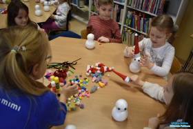 Dzieci siedzą przy stoliku i wykonują bałwanki