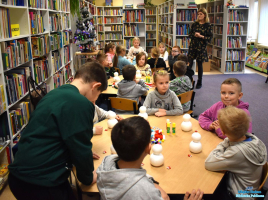 Pani stoi, a dzieci siedzą przy stolikach