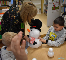 Pani stoi z maskotką obok chłopca, który siedzi przy stoliku