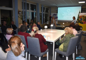 Dwie Panie stoją, a pozostali uczestnicy siedzą przy stole