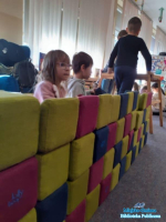 Dzieci budują ścianę z kolorowych klocków