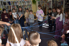 dzieci stoją w kółku i trzymają zabawkę ze sznurków