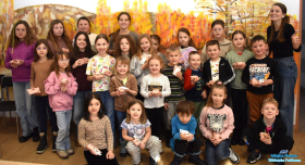 Pani wraz z dziećmi pozuje do zdjęcia, a dzieci w dłoniach trzymają gotowe prezenciki