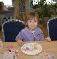 Mała dziewczynka pozuje do zdjęcia siedząc przy stole