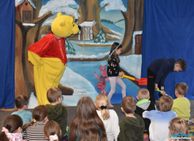 Aktor w przebraniu Kubusia Puchatka wraz z dwójka dzieci