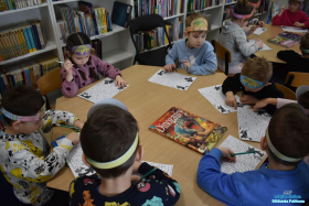 Dzieci siedzą przy stoliku i rozwiązują zagadki