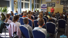 Pani stoi, a dzieci siedzą